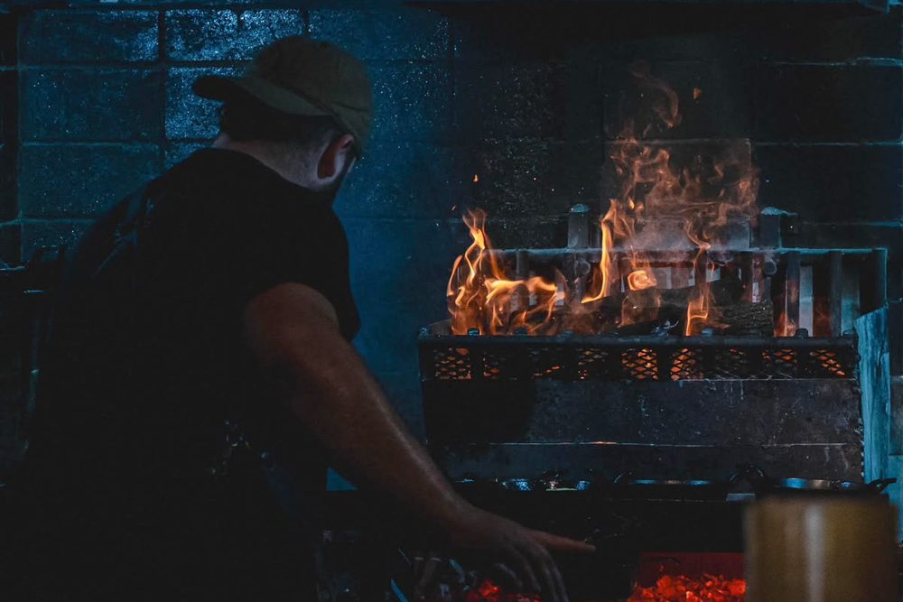 Un parrillero trabaja frente a la parrilla encendida en Eladio